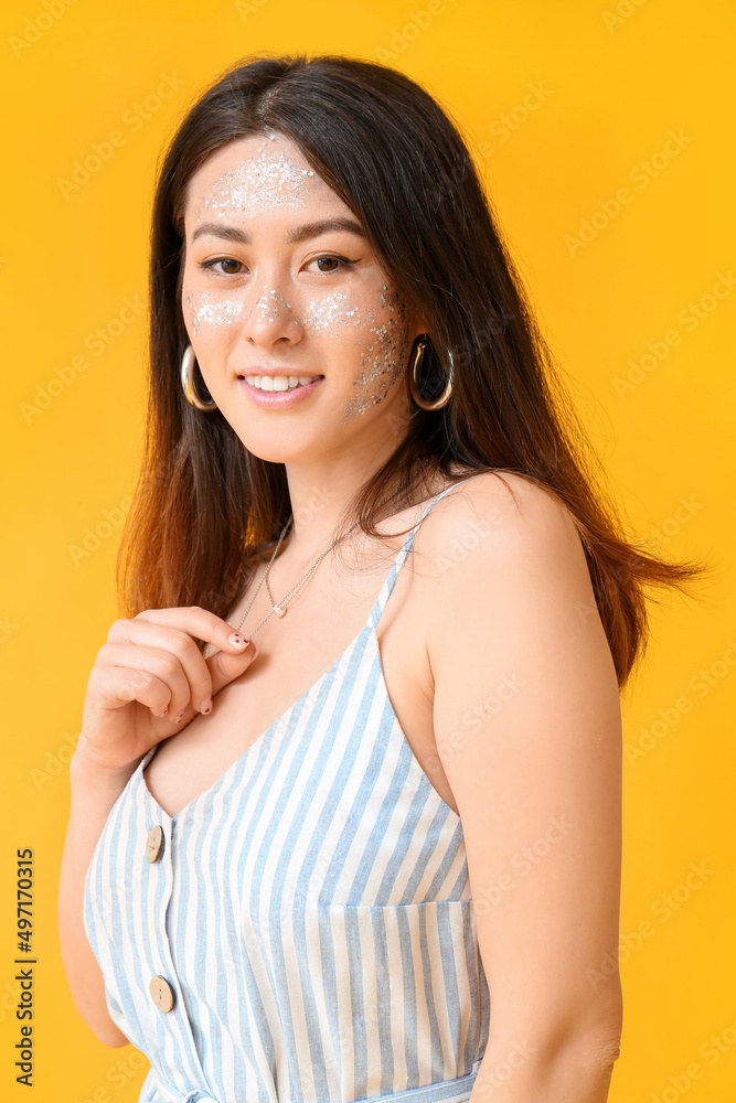 微笑的亚洲女人，彩色背景上有闪亮的妆容和项链