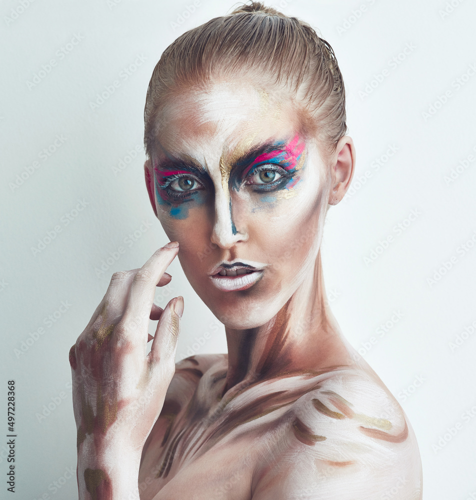 艺术中的美。一位年轻女子脸上涂着颜料摆姿势的工作室肖像。