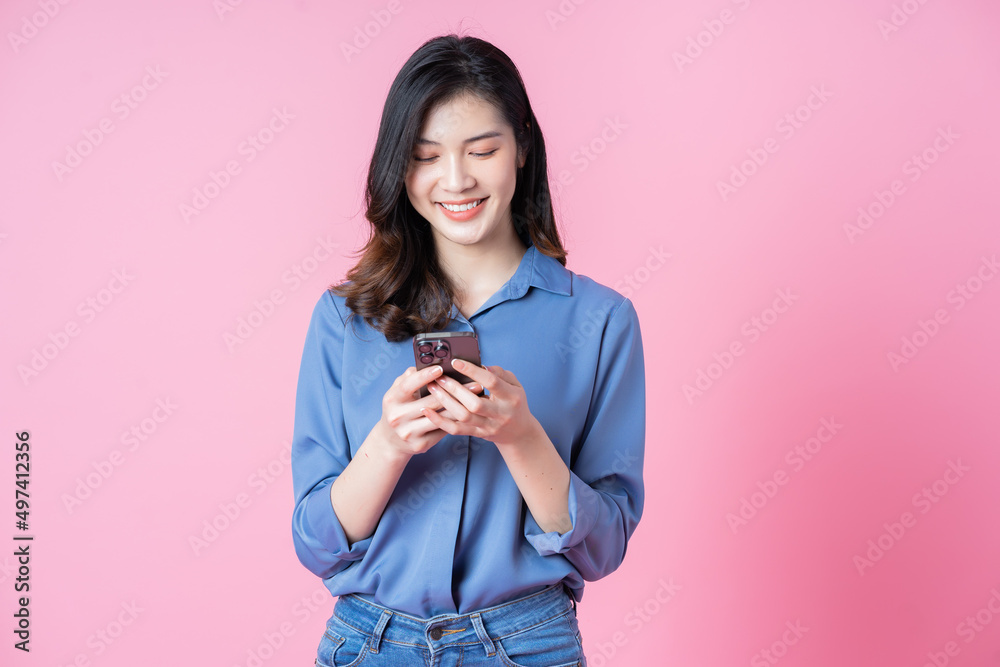 粉色背景下年轻的亚洲商务女性使用智能手机的照片
