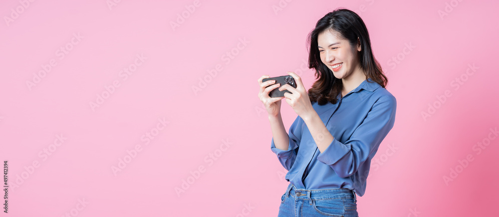 年轻的亚洲商业女性在粉色背景下使用智能手机的照片