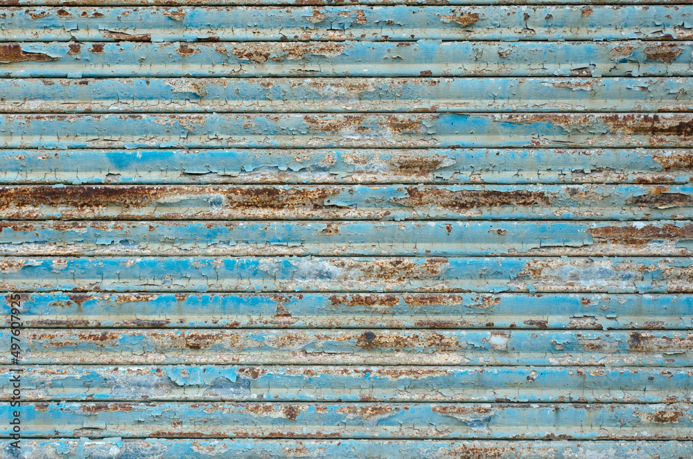 生锈的车库门。亮蓝色的油漆从生锈的铁车库门上剥落。