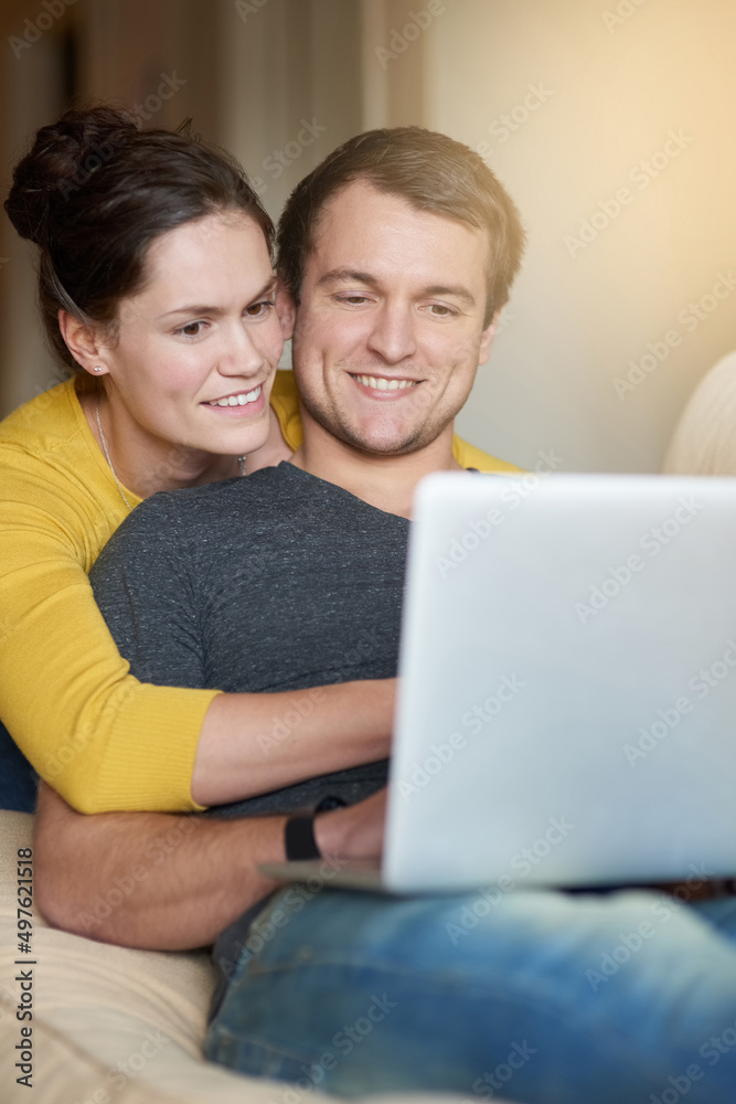 在网上为他们的新家购物。一对相爱的夫妇在家一起使用笔记本电脑的照片。