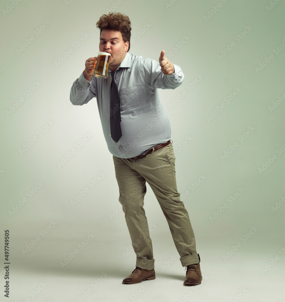 这啤酒太棒了。一个超重男子在喝一品脱啤酒时竖起大拇指的镜头。