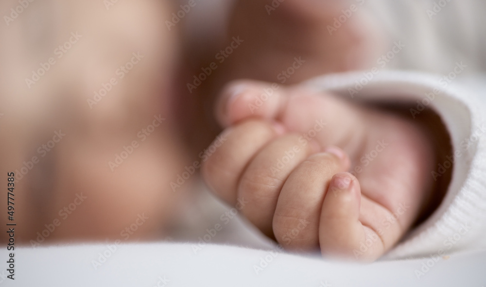 他睡得很香。一个婴儿在家睡觉时手的特写镜头。
