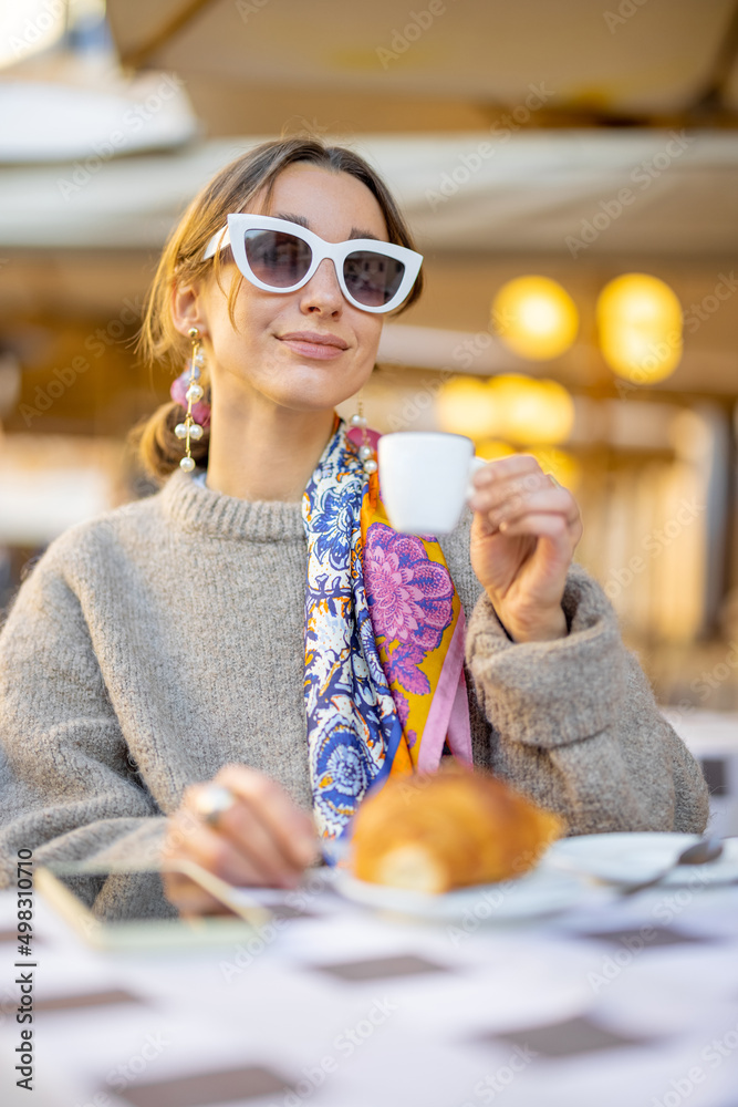 女人在传统的意大利户外咖啡馆用羊角面包和咖啡吃早餐。女人穿着