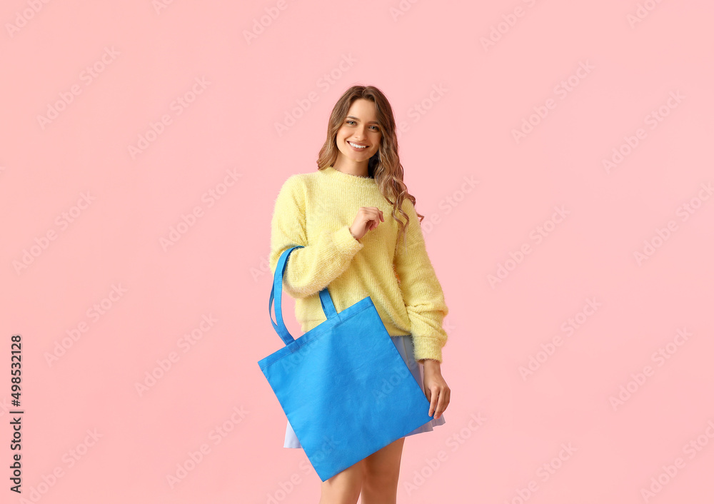 漂亮的年轻女人，粉色背景蓝色环保袋