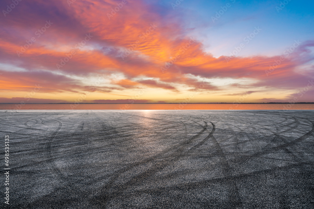 Empty asphalt road and lake with sky sunset clouds background
