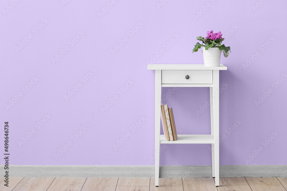 紫色墙壁附近的桌子，花盆里放着鲜花和书籍