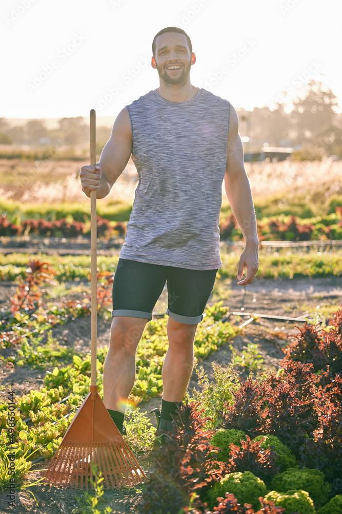 I cant wait to harvest these crops. Shot of a young man holding a rake standing in his garden.