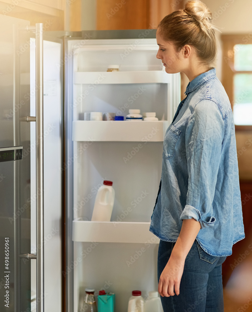 绝食时……一个年轻女人在家里看冰箱的裁剪镜头。