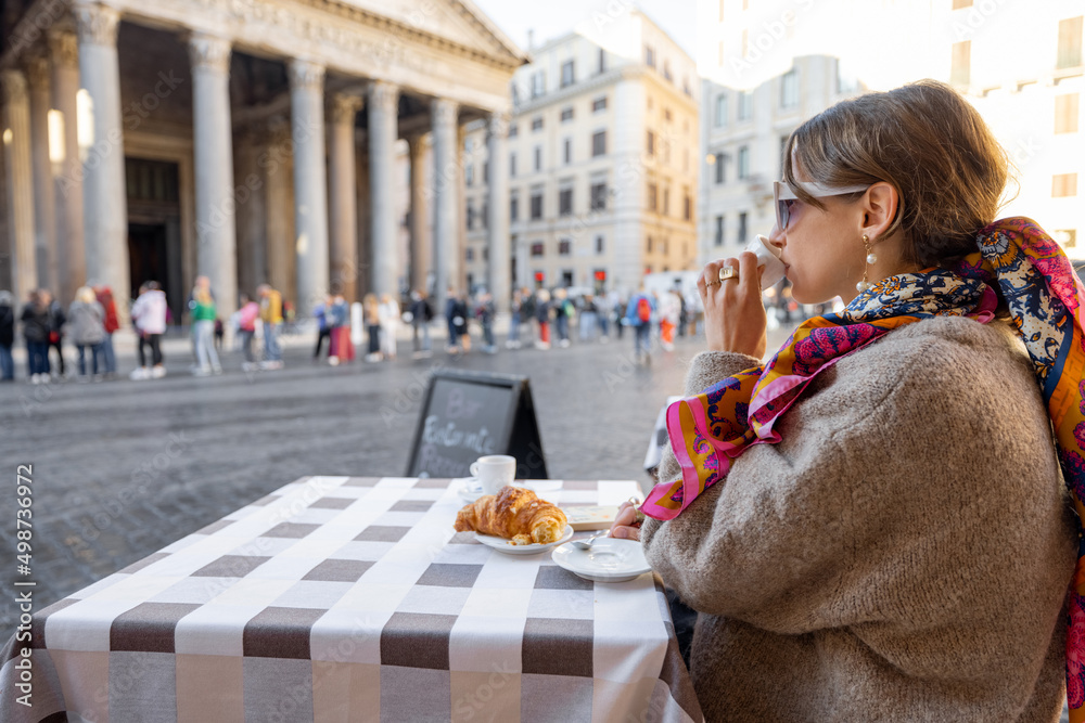 在罗马著名的万神殿附近的户外咖啡馆吃羊角面包和咖啡的女人
