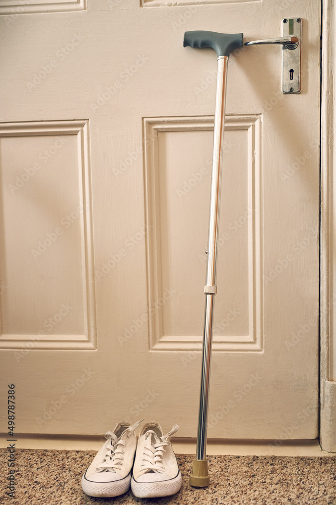 准备好散步了。一张手杖和鞋子放在养老院门口的照片。