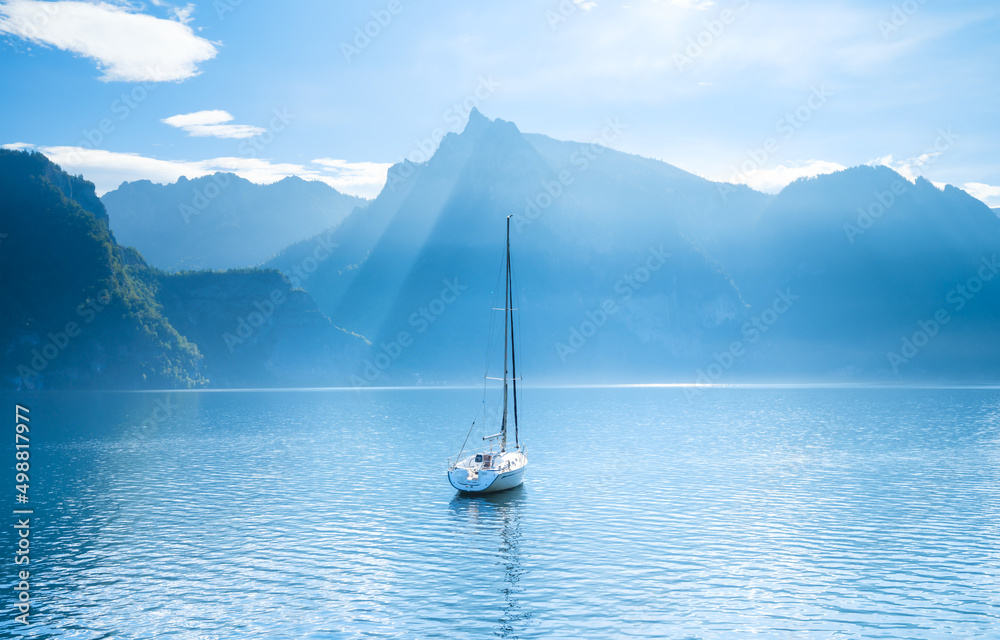 瑞士群山背景下的游艇。平静的海水和明亮的阳光。砰的一声
