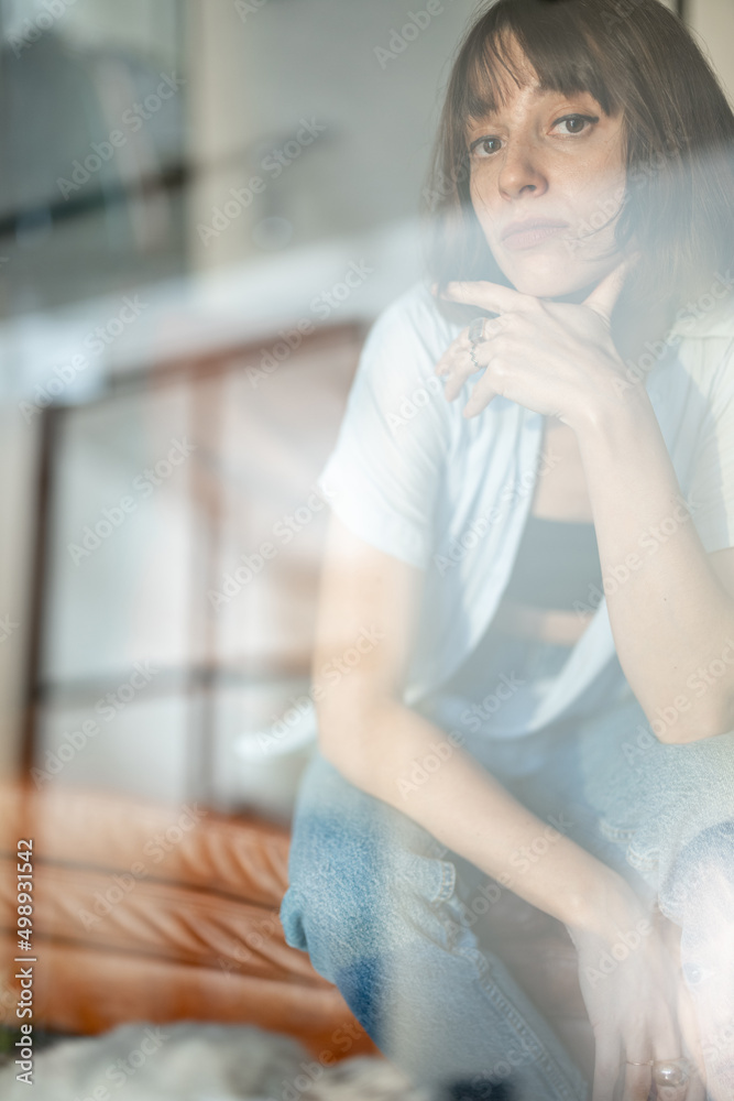 一个年轻自信的女人坐在家里沙发上的肖像。双曝光图像技术