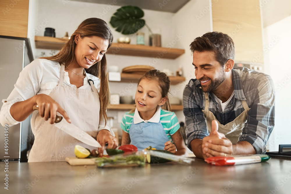 向最好的人学习。一个幸福的年轻家庭在家里的厨房里一起做饭的镜头。