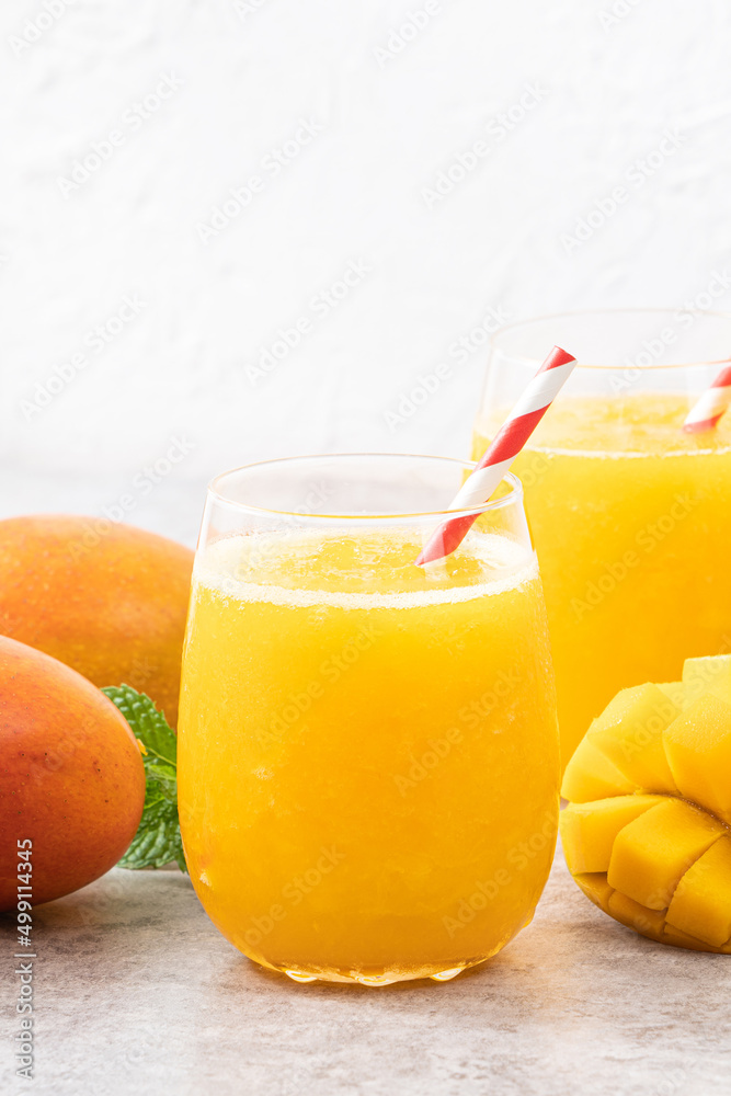 Fresh beautiful delicious mango juice smoothie in a glass cup on gray table background.