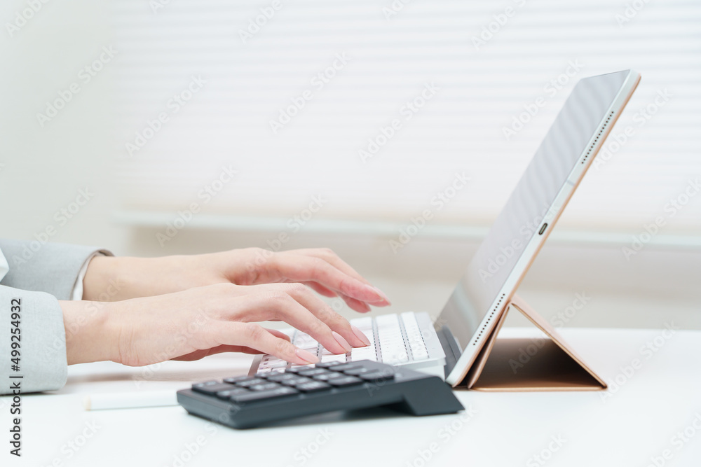パソコンのキーボードを打つ女性の手元 