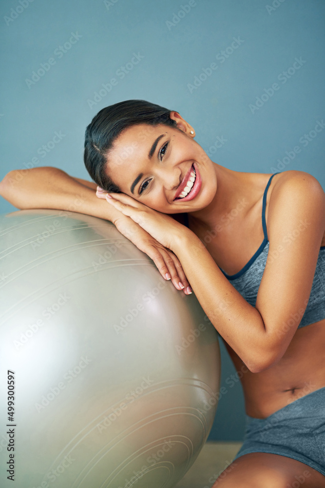 Healthy, make it your habit. Shot of a sporty young woman leaning against a pilates ball.