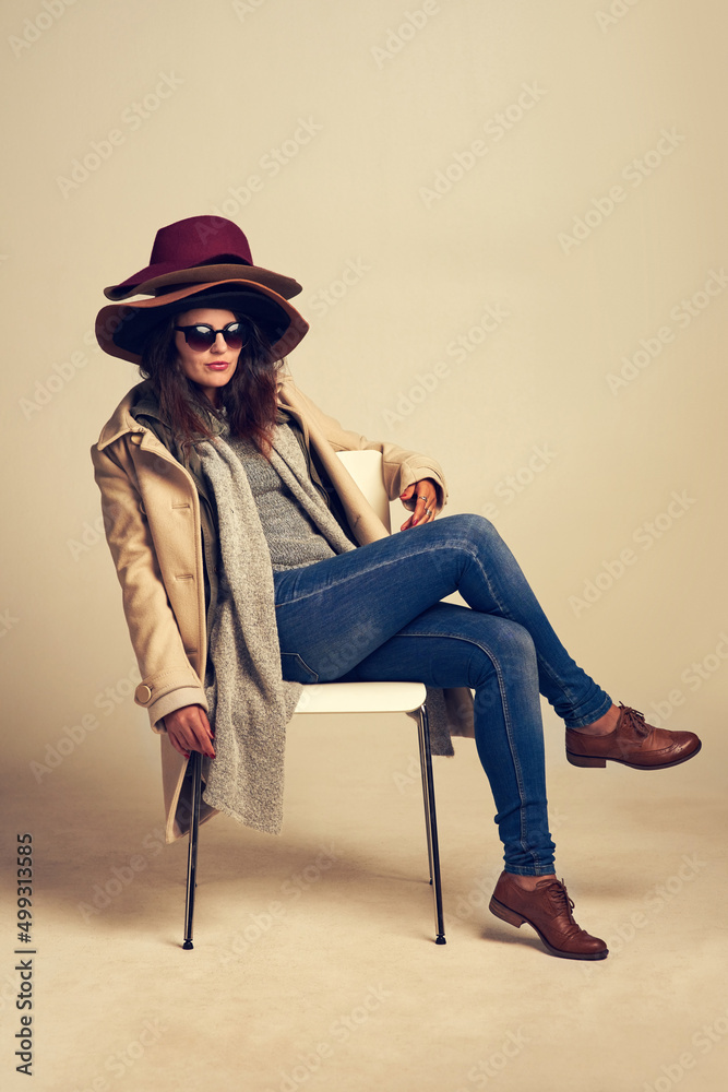 用一顶完美的帽子为你的服装锦上添花。一个年轻女人坐在椅子上疲惫的工作室镜头