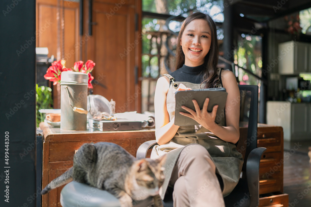 亚洲成年女性创意设计师休闲放松地在家与她的猫宠物一起工作