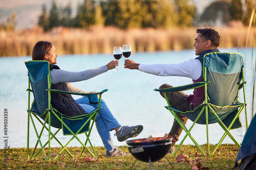 露营是一种治疗。一对年轻夫妇在外面露营时在外面喝杯饮料的照片。