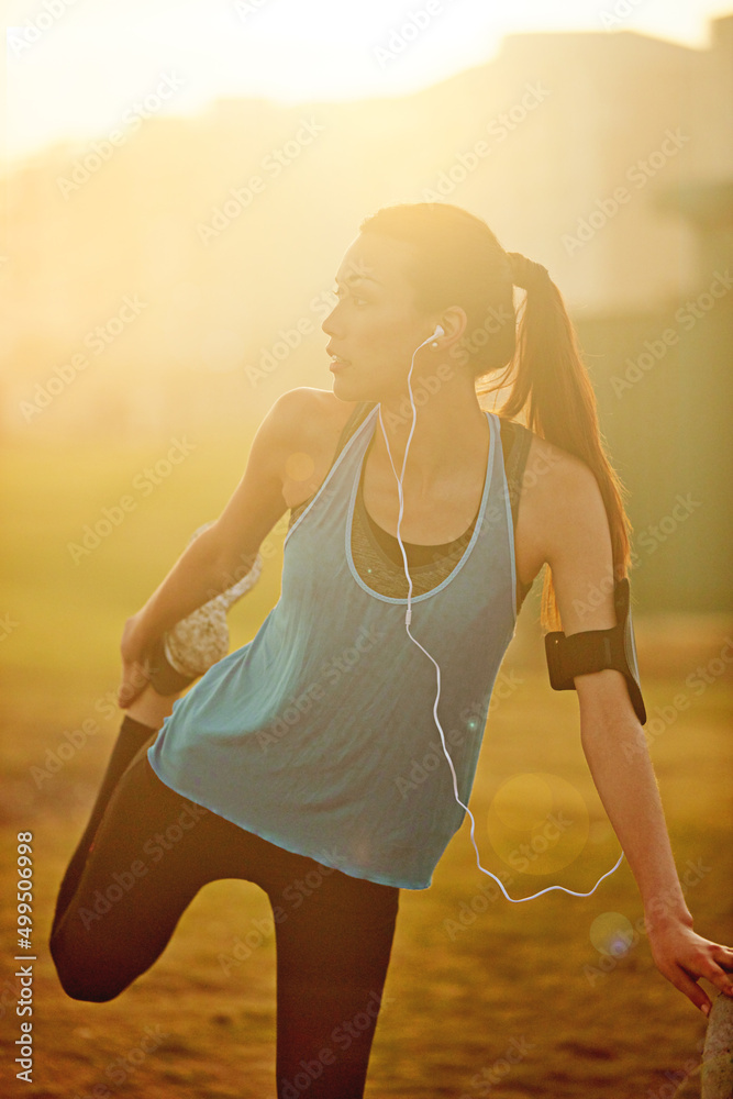锻炼肌肉。一位运动型年轻女子在跑步前拉伸的照片。