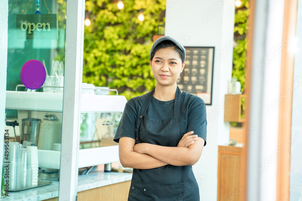 Asian barista woman standing smiling at coffee shop.