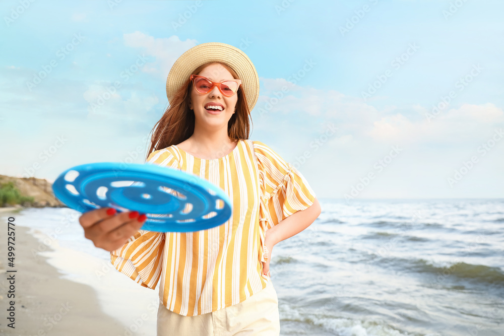快乐的年轻女子在海边玩飞盘