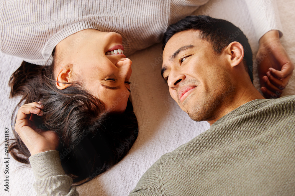 没有什么比俗气的爱情更能说明假日了。一对年轻夫妇躺在家里的地板上的照片。