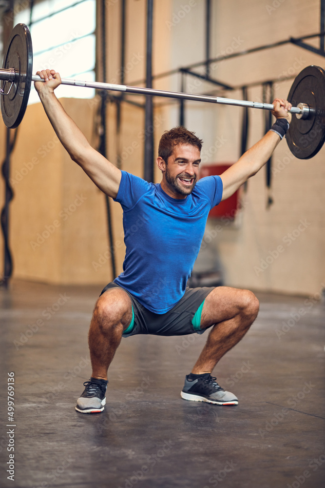 Reach your beast mode. Full length shot of a handsome young man lifting weights while working out in