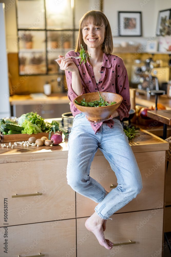 一位年轻开朗的女士穿着休闲服坐在桌子上吃健康沙拉的肖像