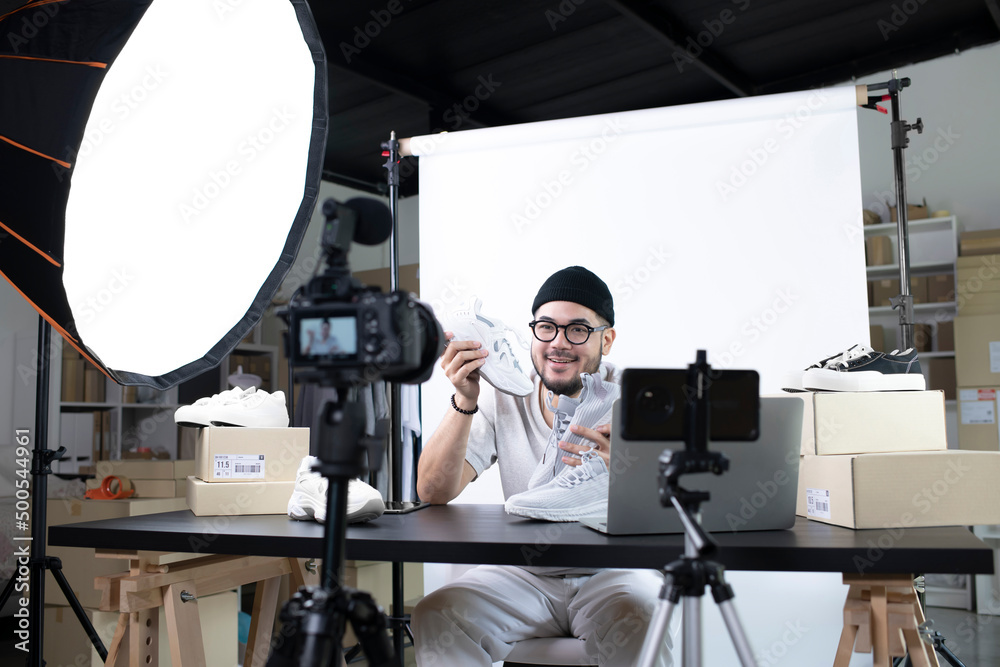 年轻有魅力的亚洲男性博主或vlogger正在查看相机评论产品。现代商人