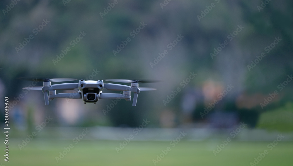 带摄像机的无人机在绿色森林表面下的天空中飞行。