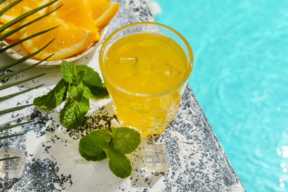游泳池边上的一杯新鲜橙色苏打水和薄荷，特写