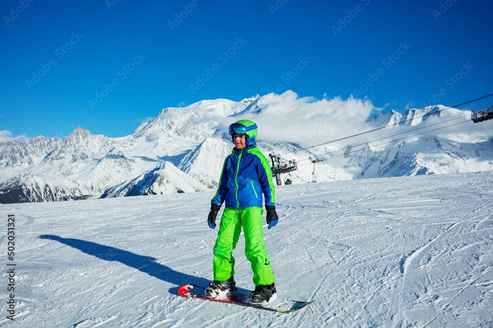 滑雪板上的男孩，穿着滑雪板全套装备，戴着头盔和口罩