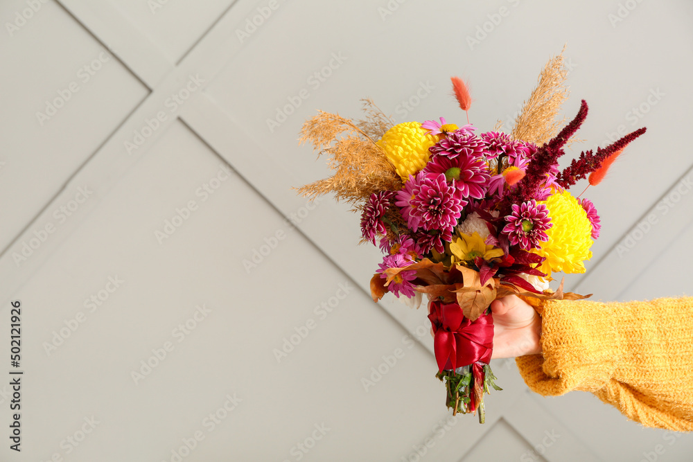 Woman with beautiful autumn bouquet on light background