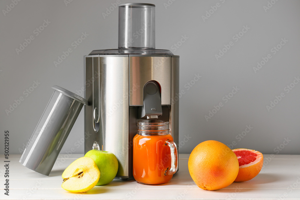 新型现代榨汁机和梅森罐新鲜果汁，桌上有水果