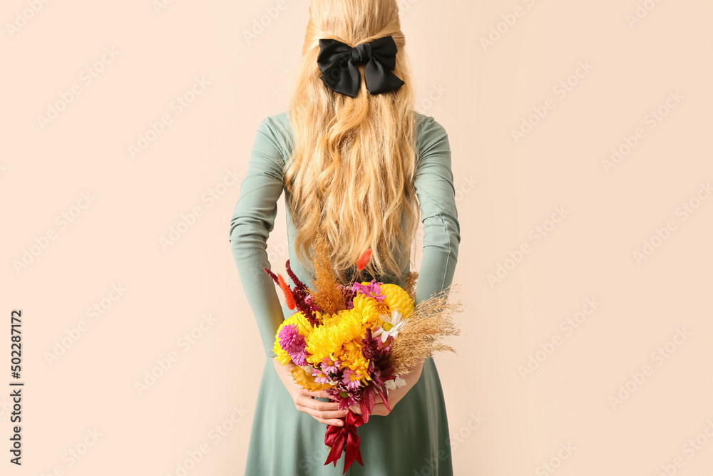 米色背景下的女人，带着美丽的秋季花束，特写