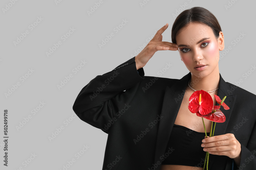 女人拿着一束灰色背景的美丽的红掌花