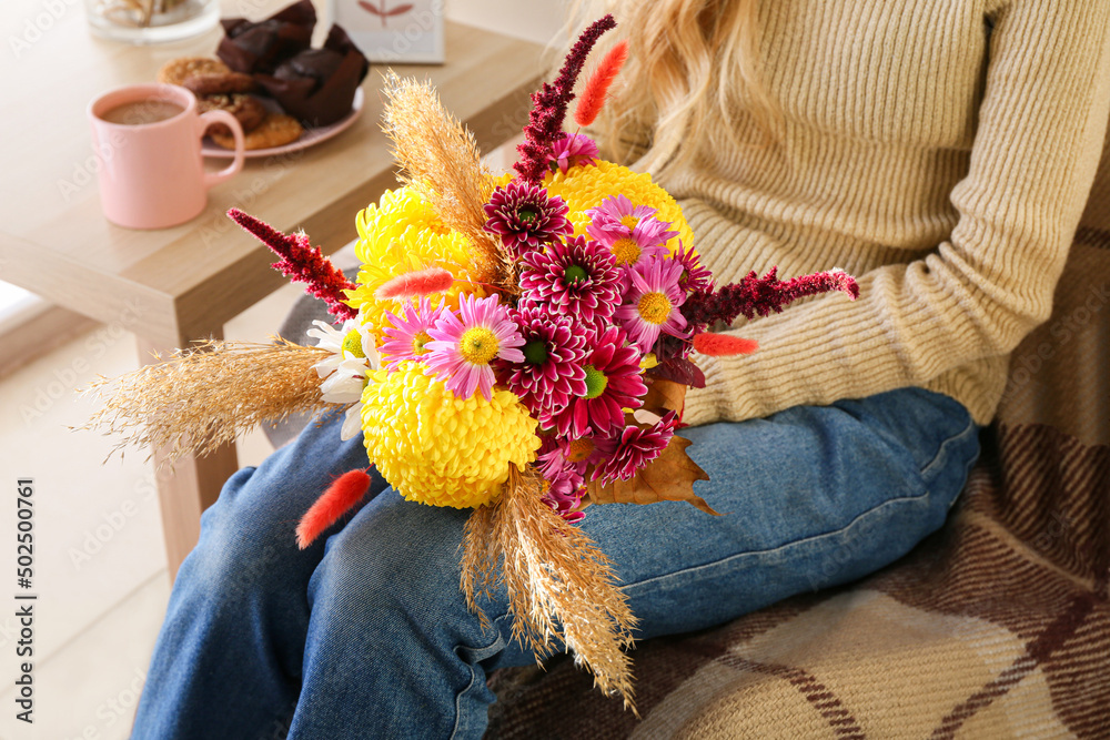 Woman with beautiful autumn bouquet sitting in armchair at home, closeup