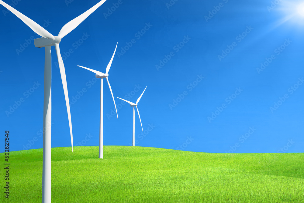 一排排风力发电机在一座绿草如茵的山丘上，映衬着深蓝色的天空，阳光普照