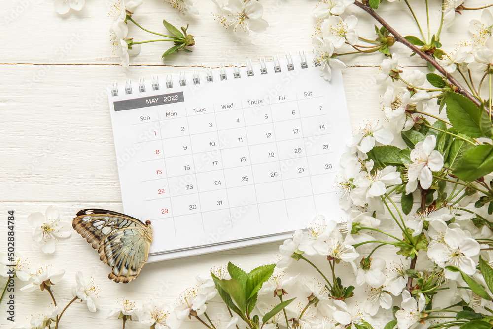白色木质背景上盛开的春枝、日历和蝴蝶