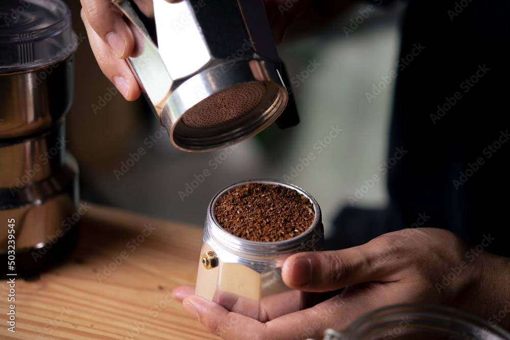 咖啡店里的咖啡师拿着装有研磨咖啡的摩卡壶。