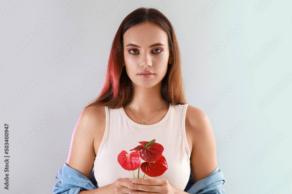在浅色背景下，美女手持一束红掌花的肖像