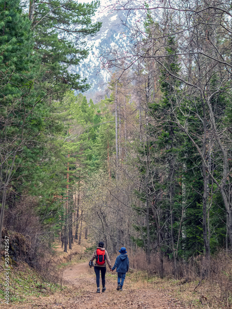 妈妈和儿子要在一条上坡的森林公路上徒步旅行。