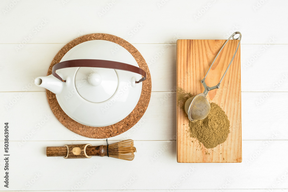 浅色木质背景上的抹茶粉、注射器、茶壶和追逐器板
