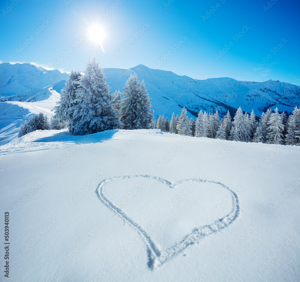 雪中的心形符号，背景是白雪皑皑的冷杉和山脉