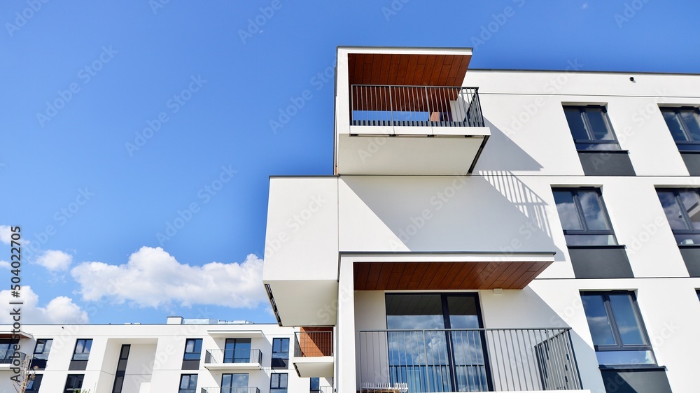 白色住宅楼的一部分，有阳台，蓝天白云。建筑细节