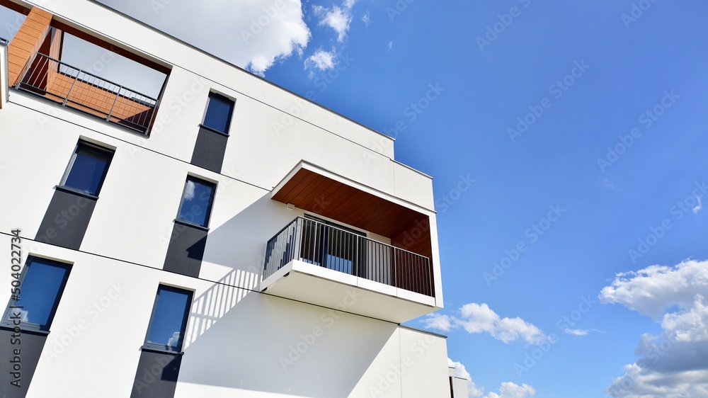 白色住宅楼的一部分，有阳台，蓝天白云。建筑细节