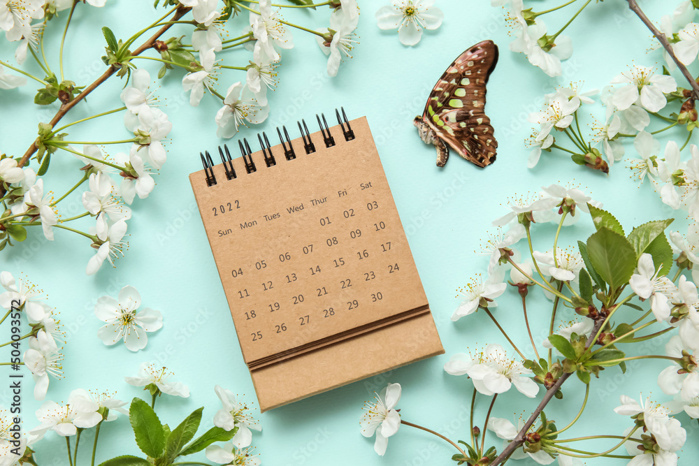 绿松石背景下盛开的春枝、日历和蝴蝶